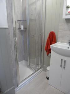 a shower with a glass door in a bathroom at Wee Ness Cottage in Inverness +20 photos