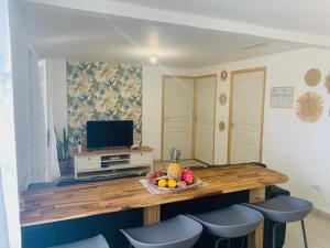 a room with a table with chairs and a television at Fleurs de mangue in Saint-Louis