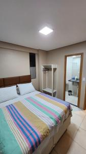 sypialnia z łóżkiem z kolorowym kocem w paski w obiekcie Flat 04 Eco Resort Carneiros w mieście Tamandaré