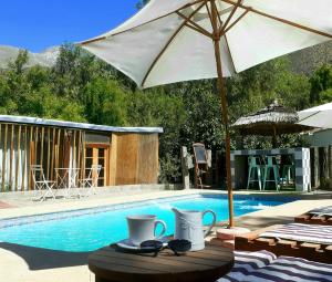 a pool with a table with an umbrella and mugs at Organica Lodge Hotel in Vicuña