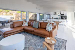 a living room with a brown couch and a kitchen at Dolphin View Beach Villa in Sedgefield