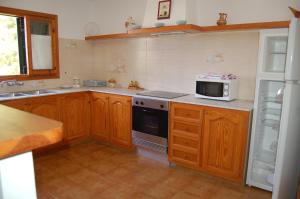 a kitchen with wooden cabinets and a stove and a microwave at Illa Colom in Cala en Bosc