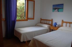 two beds in a room with a window at Illa Colom in Cala en Bosc +9 photos