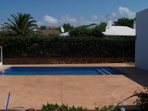 a small swimming pool in a yard with a hedge at Illa Colom in Cala en Bosc