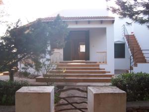 a small white house with stairs and a door at Illa Colom in Cala en Bosc