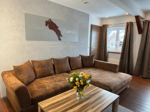 a living room with a brown couch and a table with flowers at Alte Postvilla in Oberammergau +30 photos