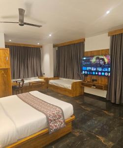 a bedroom with two beds and a flat screen tv at Vistara Residency in Navi Mumbai