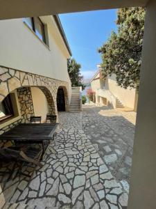 a stone walkway with a wooden bench next to a building at Bellevue Rooms in Stara Baška