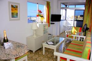 ein Wohnzimmer mit einem Stuhl und einem Tisch mit einer Flasche Wein in der Unterkunft Maritim Playa in Playa del Ingles