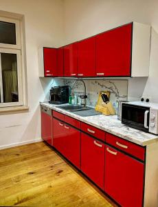 a red kitchen with a sink and a microwave at eigene Bad ruhig Öko Zentrum Zimmer Leipzig in Leipzig