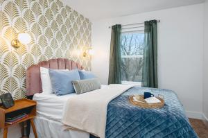 a bedroom with a bed with a blue comforter and a window at NEW Ivy House 3BR Townhome Downtown Beaches Wineries in Traverse City