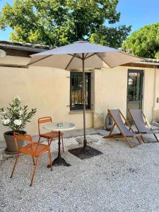 un patio avec une table, des chaises et un parasol dans l'établissement Vacances face au Luberon, à Robion