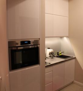 cocina con armarios blancos, fregadero y microondas en Carmen Apartment, en Cracovia