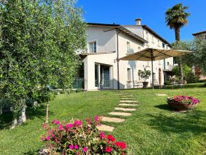 a house with a lawn with flowers and an umbrella at CorteViva Rooms in Perugia