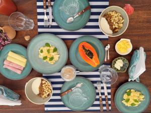 a table topped with green plates and bowls of food at Suíte Baleia in Caraíva