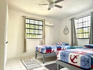 two beds in a room with two windows at South Coast - Private in Christ Church