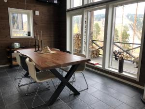 a dining room with a wooden table and chairs and windows at Storklinten 119 in Boden