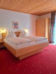 duże łóżko w sypialni z czerwonym dywanem w obiekcie Appartement Bergkristall w mieście Sankt Johann im Pongau