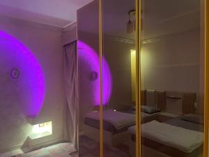 Habitación con 2 camas y espejo con luces moradas. en Luxury 3 bedrooms apartment for rent in a sheikh zayed compound, en Kafr Abū ʼumaydah