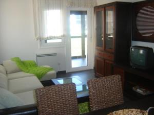 sala de estar con sofá y TV en Apartamento Viveiro, Terraza, 2 dormitorios 2 baños, piscina, parking, tenis, en Jove (Xove)