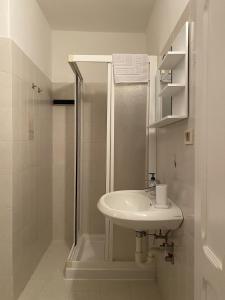 a white bathroom with a shower and a sink at GolfHouseApartment in Bocenago