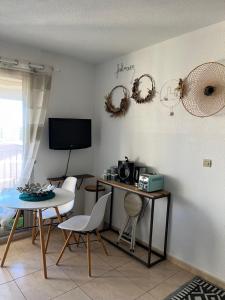 a living room with a table and chairs and a television at Appartement Cosy, au pied de la plage du Grazel. in Gruissan