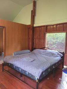 a bed in a room with a wooden wall at Salawin Fruit Jungle Farmstay in Ban Sob Moei