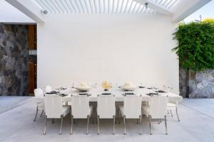 a white dining room with a long table and white chairs at Casa Brisa Luxury on The Beach in Punta Mita