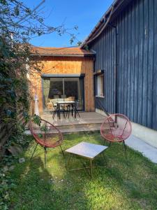 two red chairs and a table in a yard at INSTANT ZEN in Saint-Vivien-de-Médoc