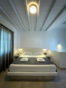 a white room with a bed with two towels on it at ANETON Residences in Karavostasi