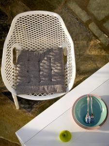 a white wicker chair with a pillow and a bowl at ANETON Residences in Karavostasi