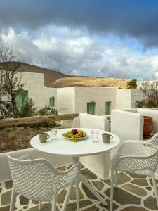 a white table and chairs with a plate of fruit at ANETON Residences in Karavostasi