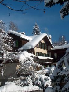 una casa cubierta de nieve delante en FERIENWOHNUNGEN Chalet Hohturnen, en Grindelwald