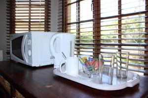 a microwave sitting on a table next to a tray with cups at Bodulo Lodge in Thaba Nchu