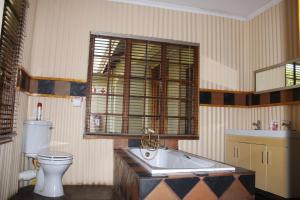 a bathroom with a tub and a toilet and a sink at Bodulo Lodge in Thaba Nchu +38 photos