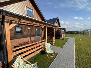 a house with a deck and two chairs next to it at Zielona Dolina Sarbinowo in Sarbinowo