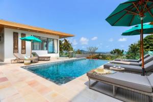 a swimming pool with chairs and umbrellas next to a house at Amazing Luxury Villa in Ban Thung