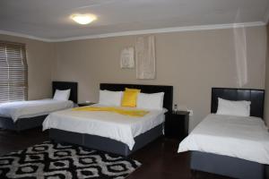 a bedroom with two beds with white and yellow pillows at Bodulo Lodge in Thaba Nchu