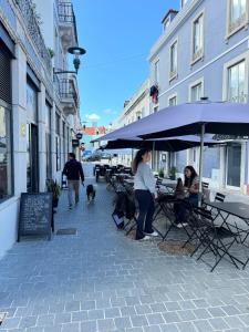 a group of people sitting under umbrellas on a street at Cozy apartment in Paço de Arcos