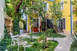 une maison jaune avec des chaises et des arbres devant elle dans l'établissement Luxurious Villa with Lush Garden and Huge Terrace near Herastrau Park, à Bucarest