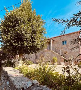a stone house with a tree in front of it at Vila Adelaide in Campos