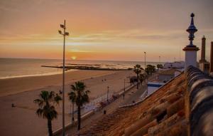 a view of a beach at sunset with a lighthouse at Recidencial Cruz del Mar "Duplex Villa Amanecer" in Chipiona