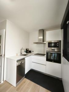a white kitchen with a sink and a microwave at Recidencial Cruz del Mar "Duplex Villa Amanecer" in Chipiona