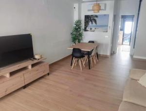 a living room with a television and a table and chairs at Recidencial Cruz del Mar "Duplex Villa Amanecer" in Chipiona