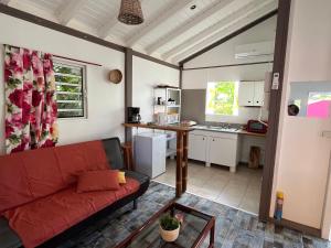 een woonkamer met een rode bank en een keuken bij LES BUNGALOWS DE LOUISIANE in Saint-François