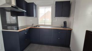 a kitchen with black cabinets and a sink and a window at L'Écrin de Sérénité in Wervicq-Sud