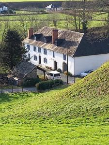 a white house on a hill with cars parked in front at Gîte Lagrave in Arette