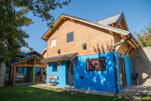 una casa azul con techo de madera en Sherpa Hostel en San Martín de los Andes