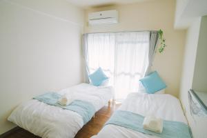 zwei Einzelbetten in einem Zimmer mit Fenster in der Unterkunft MinamiFukuokaHouse in Fukuoka