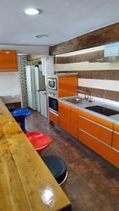 eine Küche mit orangefarbenen Schränken und einem Holztisch in der Unterkunft La herradura de San Pedro II in Arenas de San Pedro
